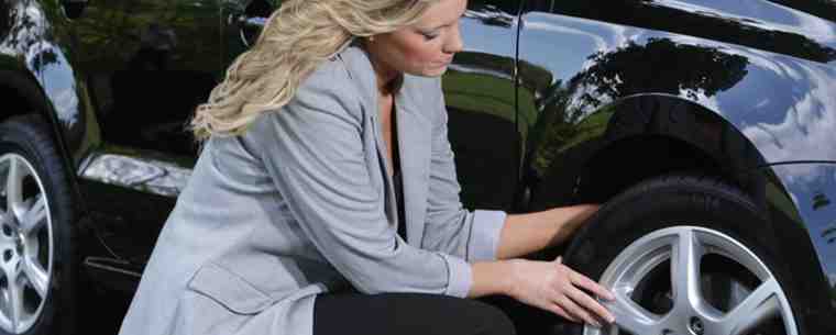 woman checking tyre for wear and damage