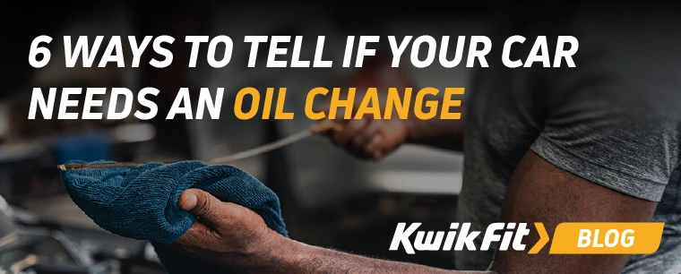 Technician wiping a cars oil dipstick with a cloth.