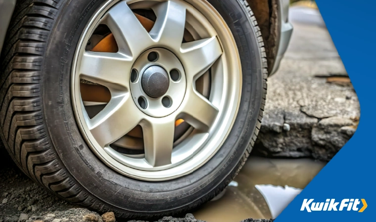 Car tyre in pothole.