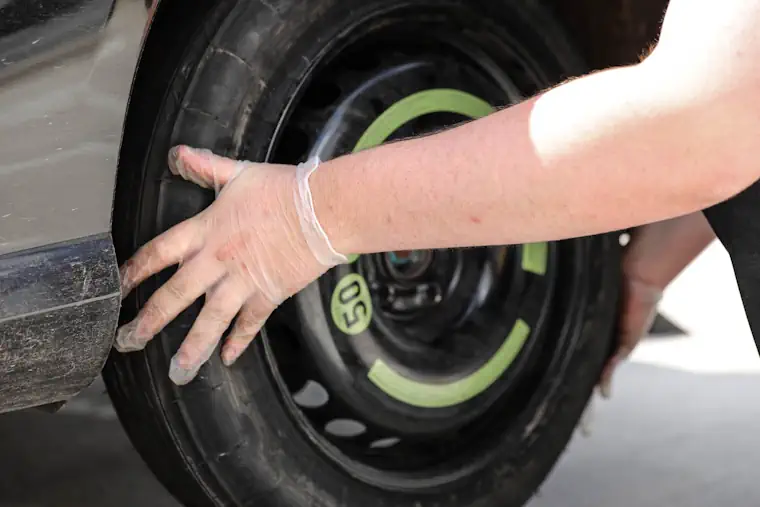 Person fitting a spare wheel onto a car.