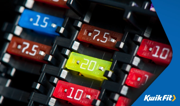 Close up of different blade fuses in a car's fuse board showing different amp ratings.