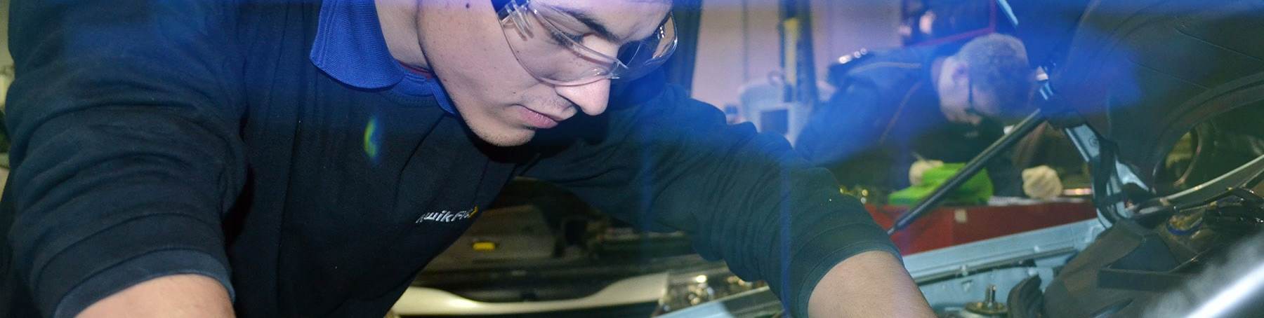 Kwik Fit apprentice looking at car engine