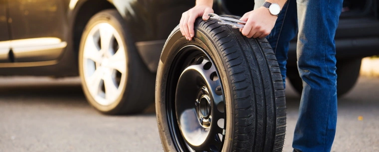 Person changing a spare tyre on the side of a road