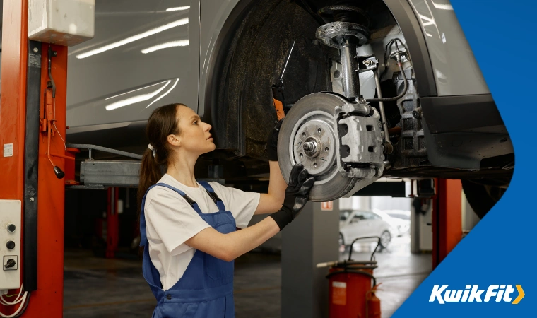 A mechanic inspects the condition of a car's brakes.