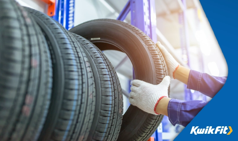 A mechanic taking a new tyre off the rack.