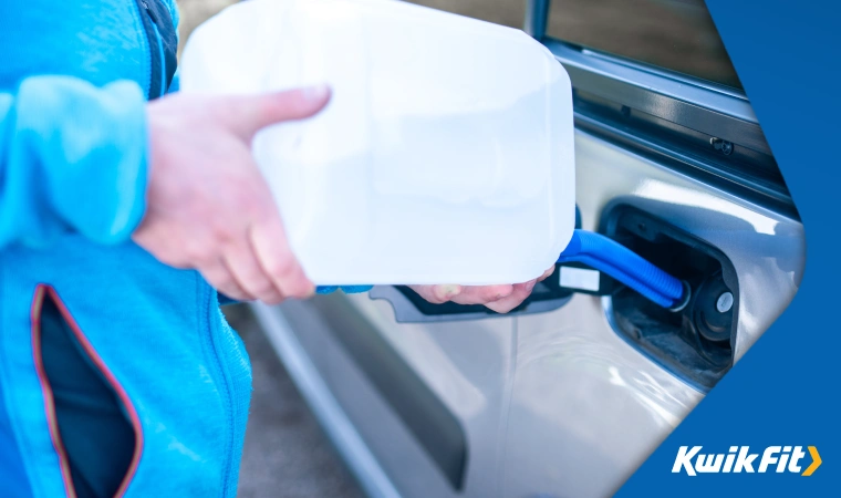 Person in blue fleece refilling the AdBlue tank of their car.