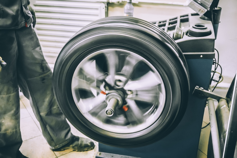 A Kwik Fit technician operates a wheel balancing machine with a tyre on it.