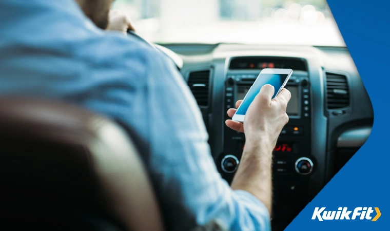 Man looking at his mobile phone while driving.