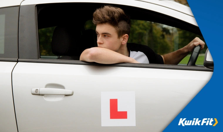 Student driver reversing with learner plate on car door.