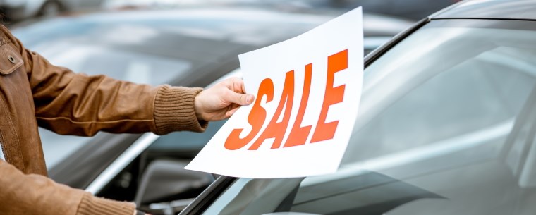 Man putting for sale sticker on car windshield